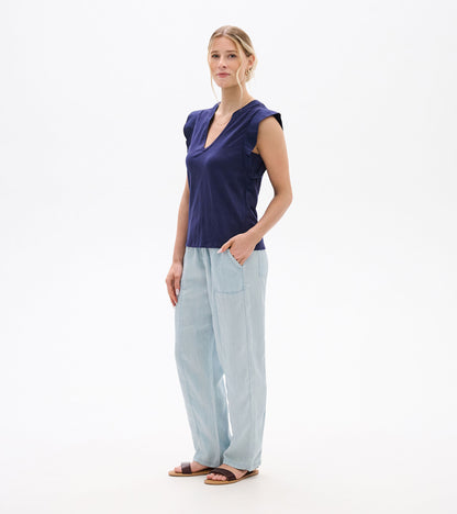 Woman wearing a navy sleeveless V-neck tank top with ruffled shoulders and a relaxed fit, front view.