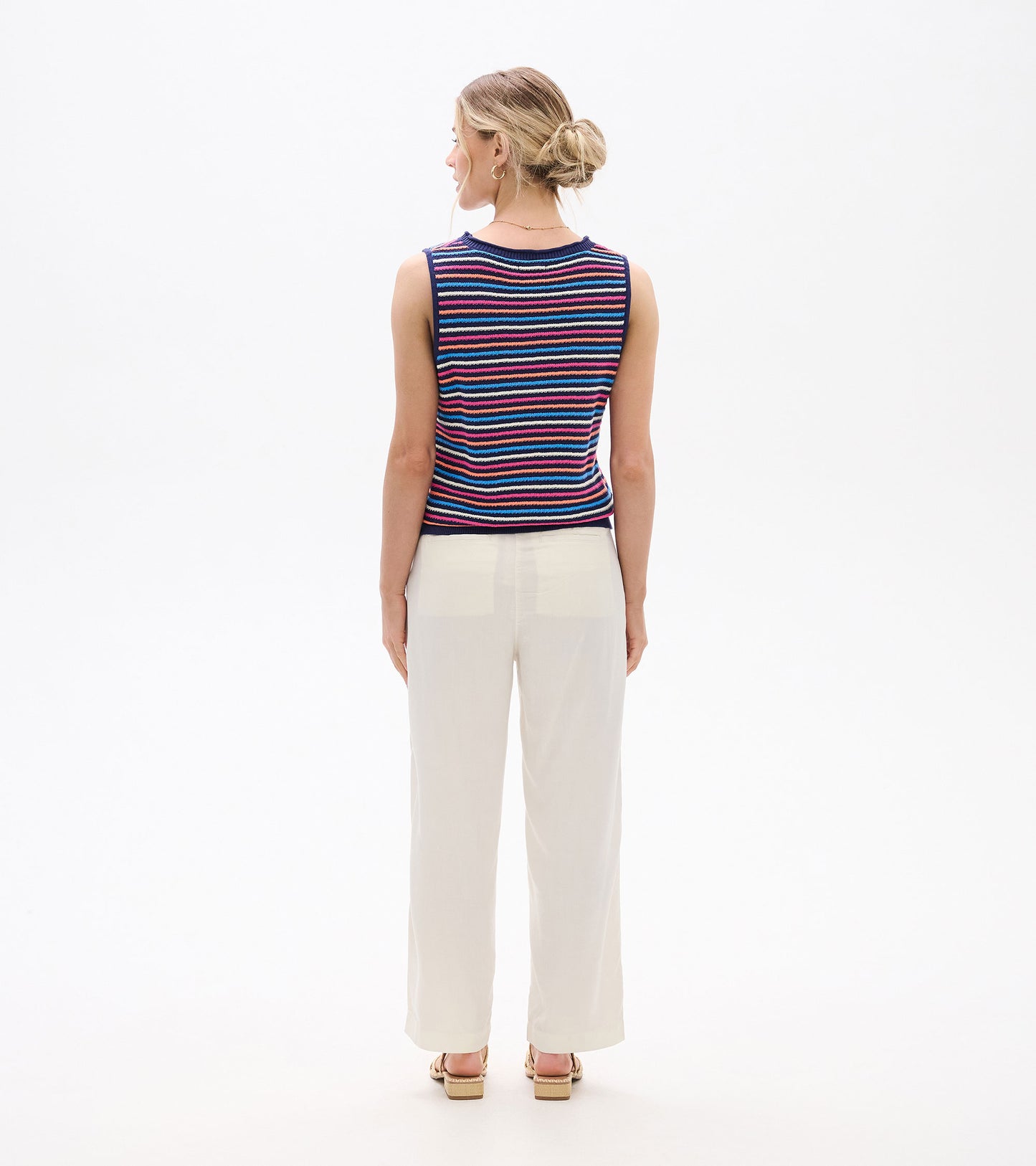 Back view of sleeveless knit tank with multicolor horizontal stripes and navy trim, worn with light pants.