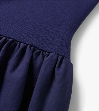 Close-up of a navy blue midi dress with a ribbed knit bodice and gathered ruffle skirt seam.