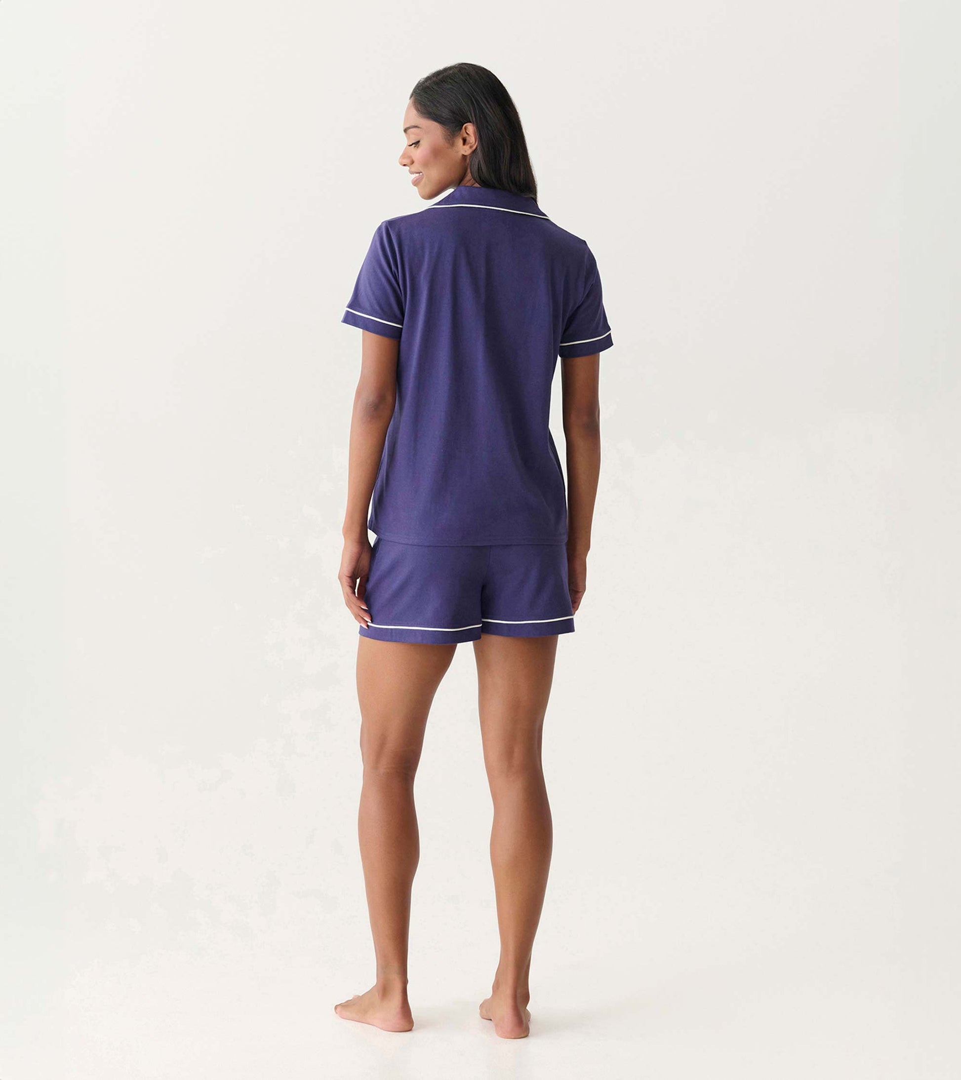 Back view of women's navy short pajama set with white piping