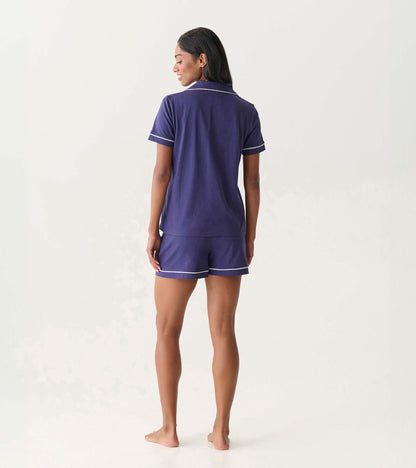 Back view of women's navy short pajama set with white piping