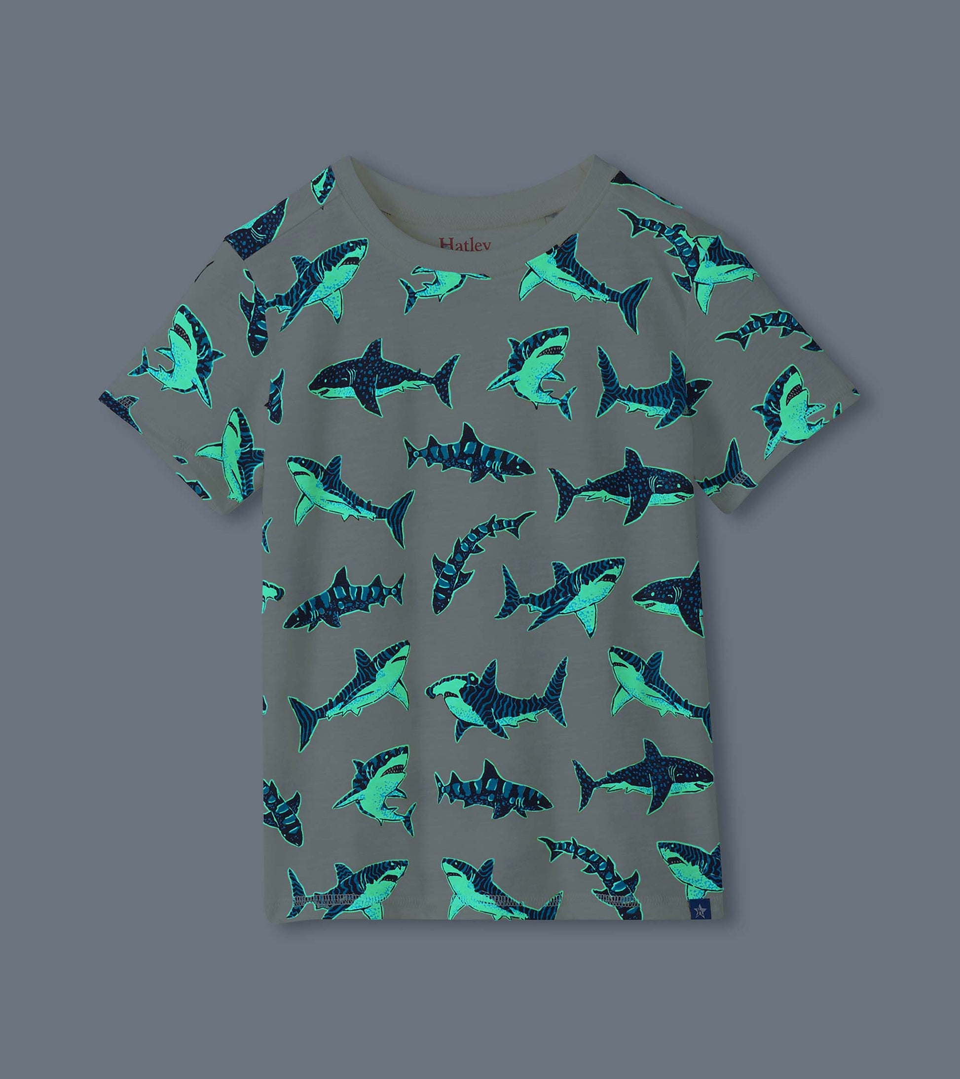 Cream boys shark print tee shown glowing in the dark with bright blue shark outlines