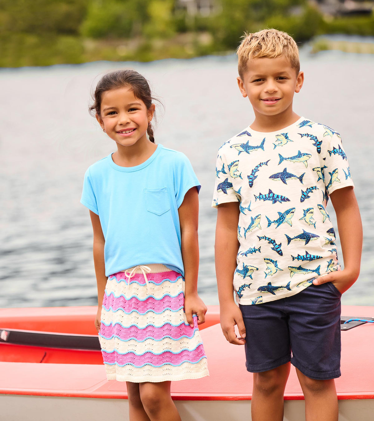 Boy wearing heathered natural shark print tee with navy shorts, standing beside another child by the water