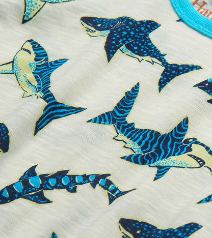 Close-up of white fabric with blue and teal shark print on a boys raglan T-shirt