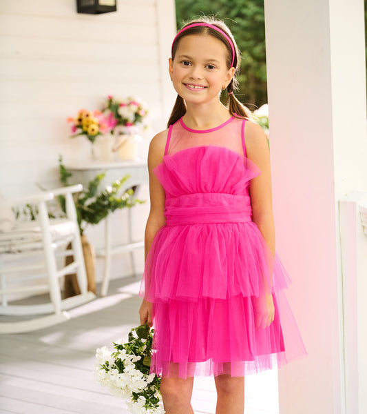 Girl wearing a fuchsia tiered tulle party dress with sheer neckline and ruched waistband