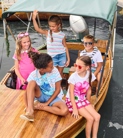 Girls multicolor striped sleeveless crochet tank top with white trim, shown on a child standing on a boat