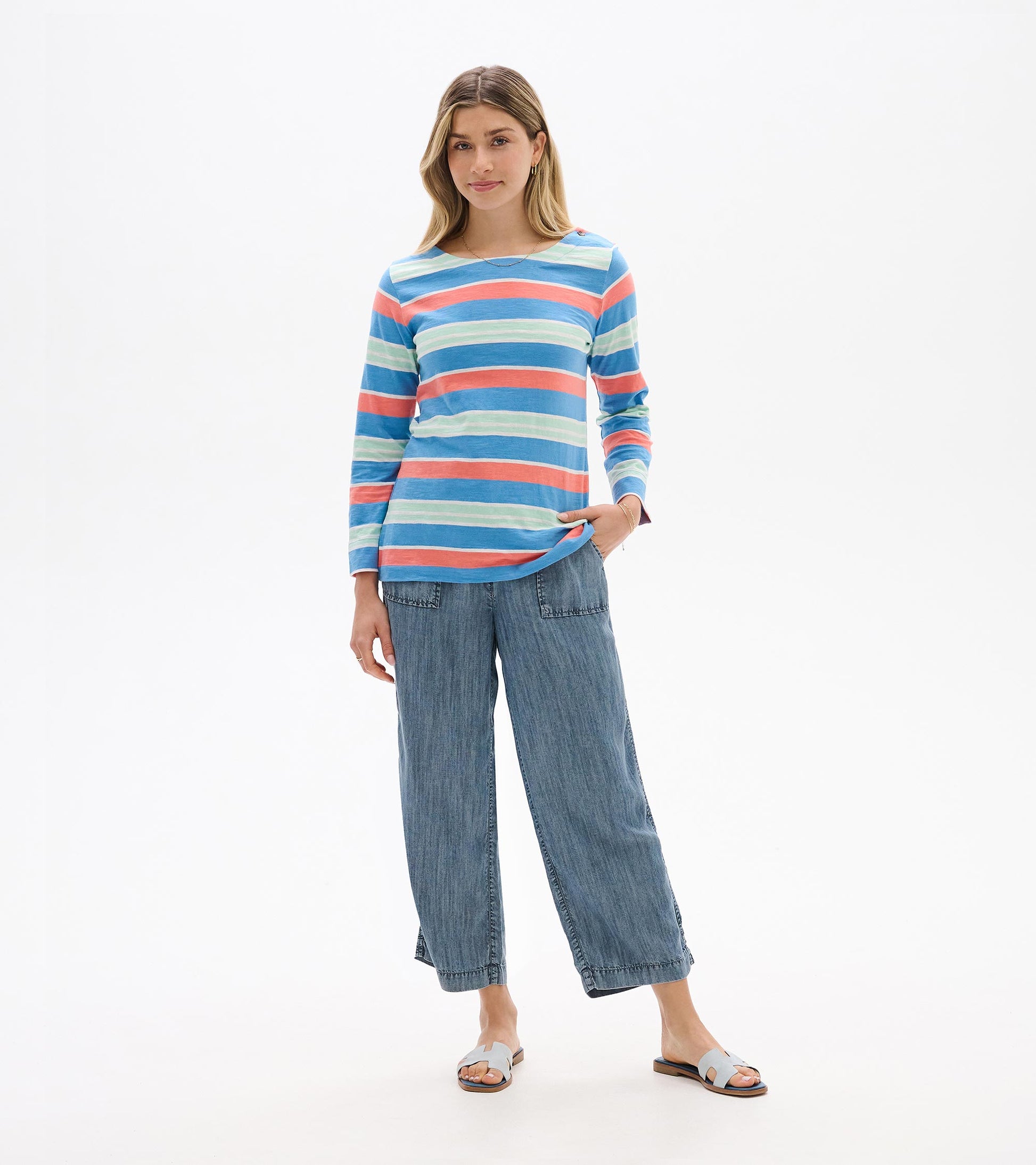 Woman wearing a long-sleeve striped top in blue, coral, and mint with a scoop neck, front view