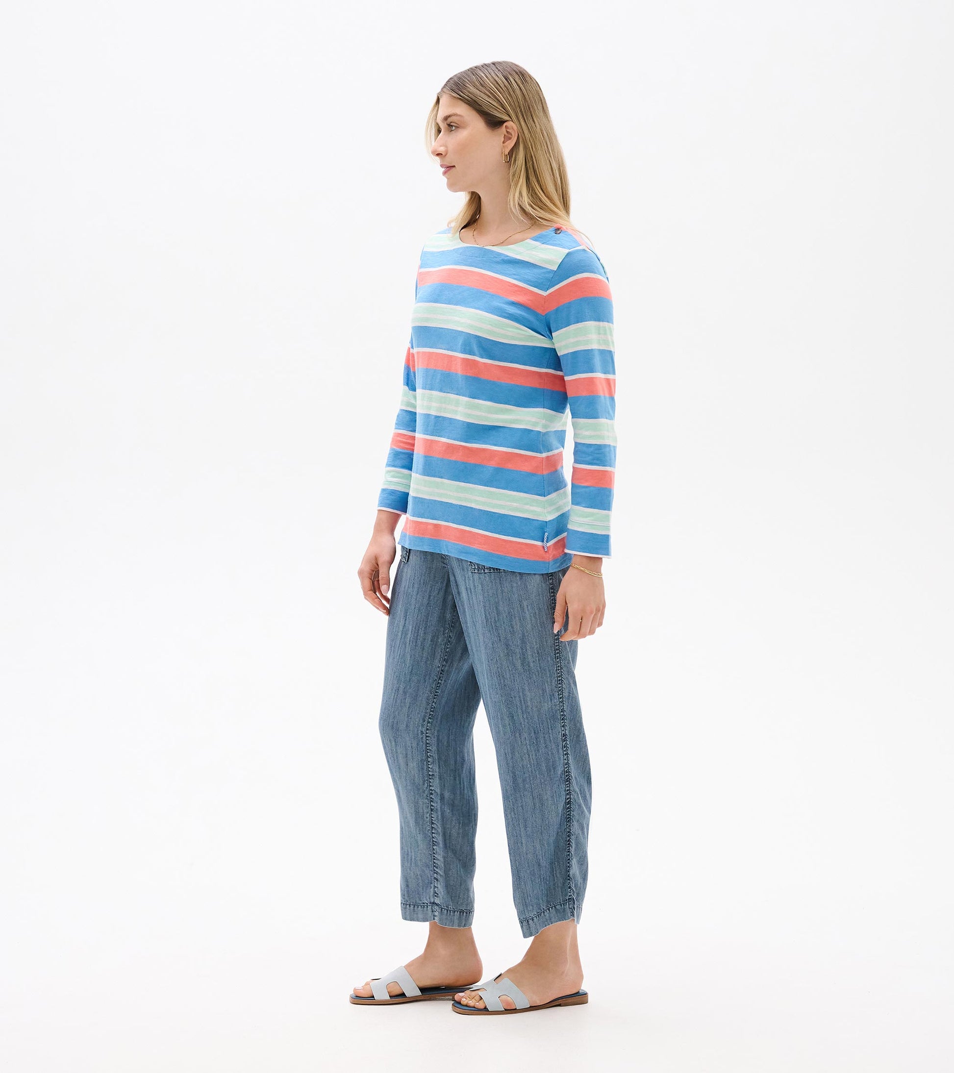 Long-sleeve striped top in blue, coral, and mint with a boat neckline, shown on a model in side view.