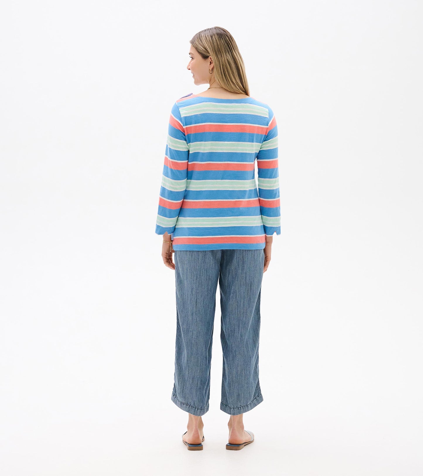 Back view of a blue striped long-sleeve top with coral and mint horizontal stripes, worn with cropped jeans.