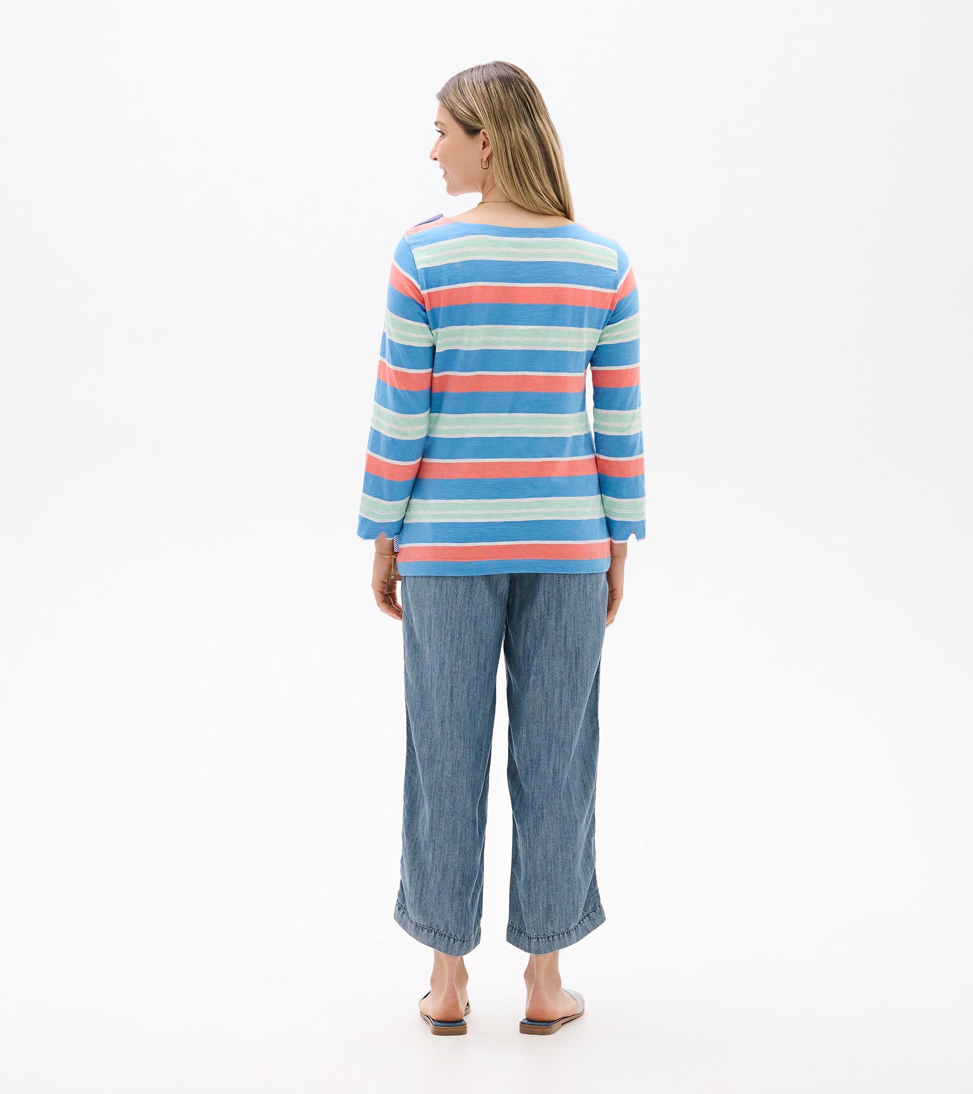 Back view of a blue striped long-sleeve top with coral and mint horizontal stripes, worn with cropped jeans.