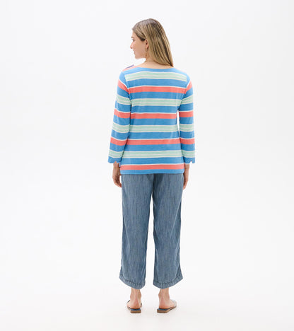 Back view of a blue striped long-sleeve top with coral and mint horizontal stripes, worn with cropped jeans.