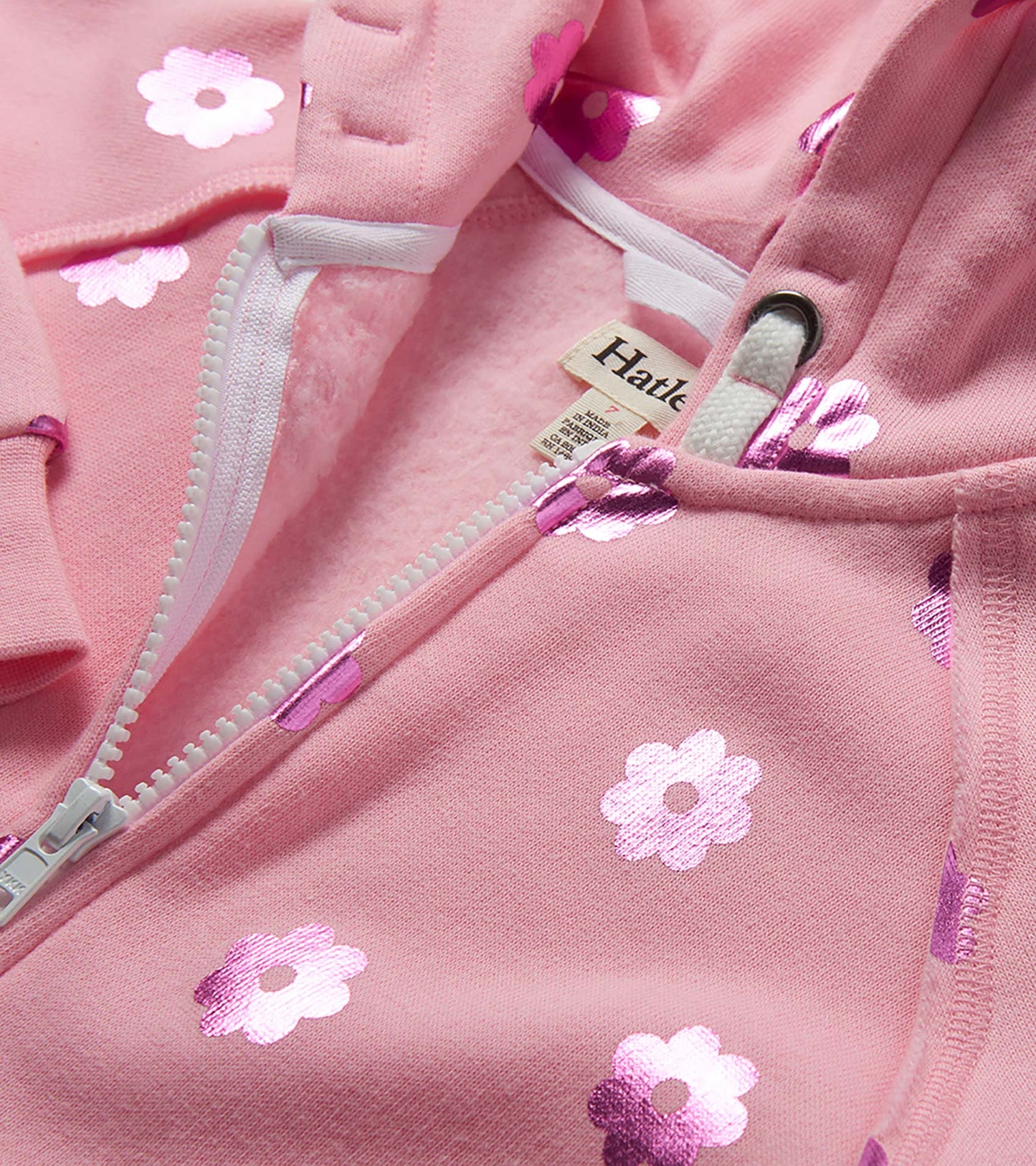 Pink girls zip-up hoodie with white flower print and drawstring hood, close-up front view