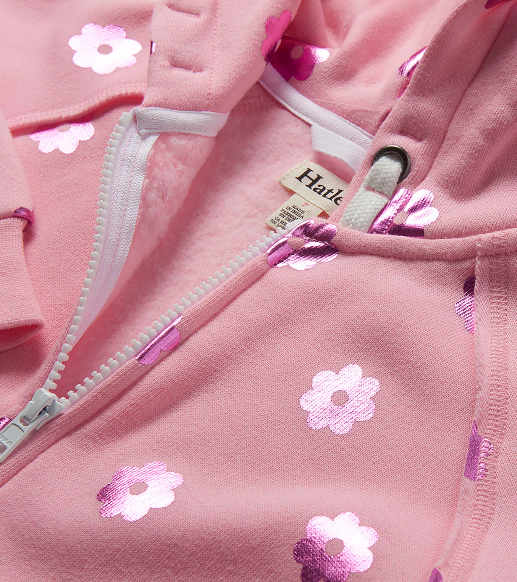 Pink girls zip-up hoodie with white flower print and drawstring hood, close-up front view