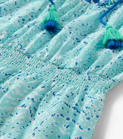 Close-up of Chloe Dress in beach glass ikat print with smocked waist and blue-green tassel ties