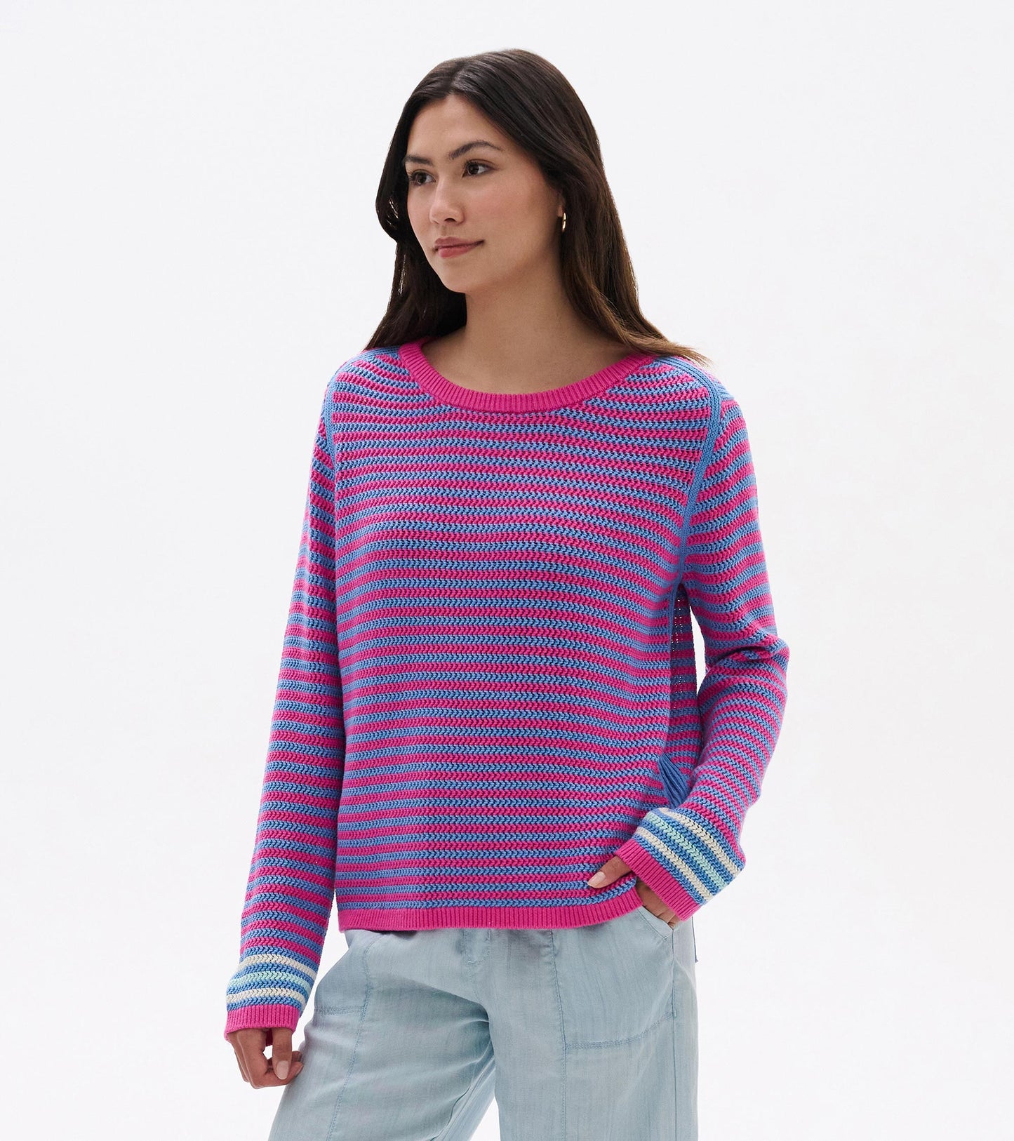 Woman wearing a pink and blue striped knit sweater with long sleeves and a crew neckline
