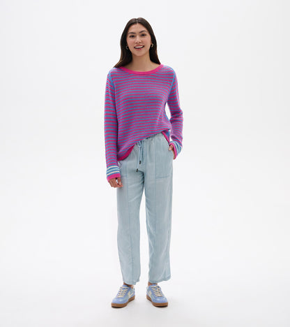 Woman wearing a pink and blue striped pointelle sweater with long sleeves and crew neck, front view