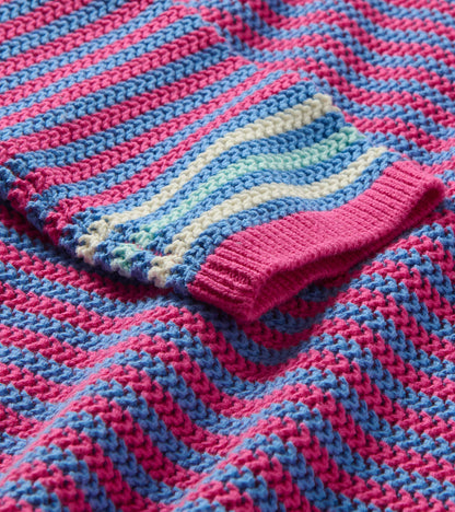 Close-up of a pink and blue striped knit sweater with ribbed cuff and pointelle texture