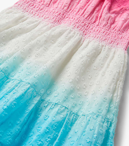 Close-up of a pink, white, and blue dip-dye gathered dress with textured fabric and ruffled tiers