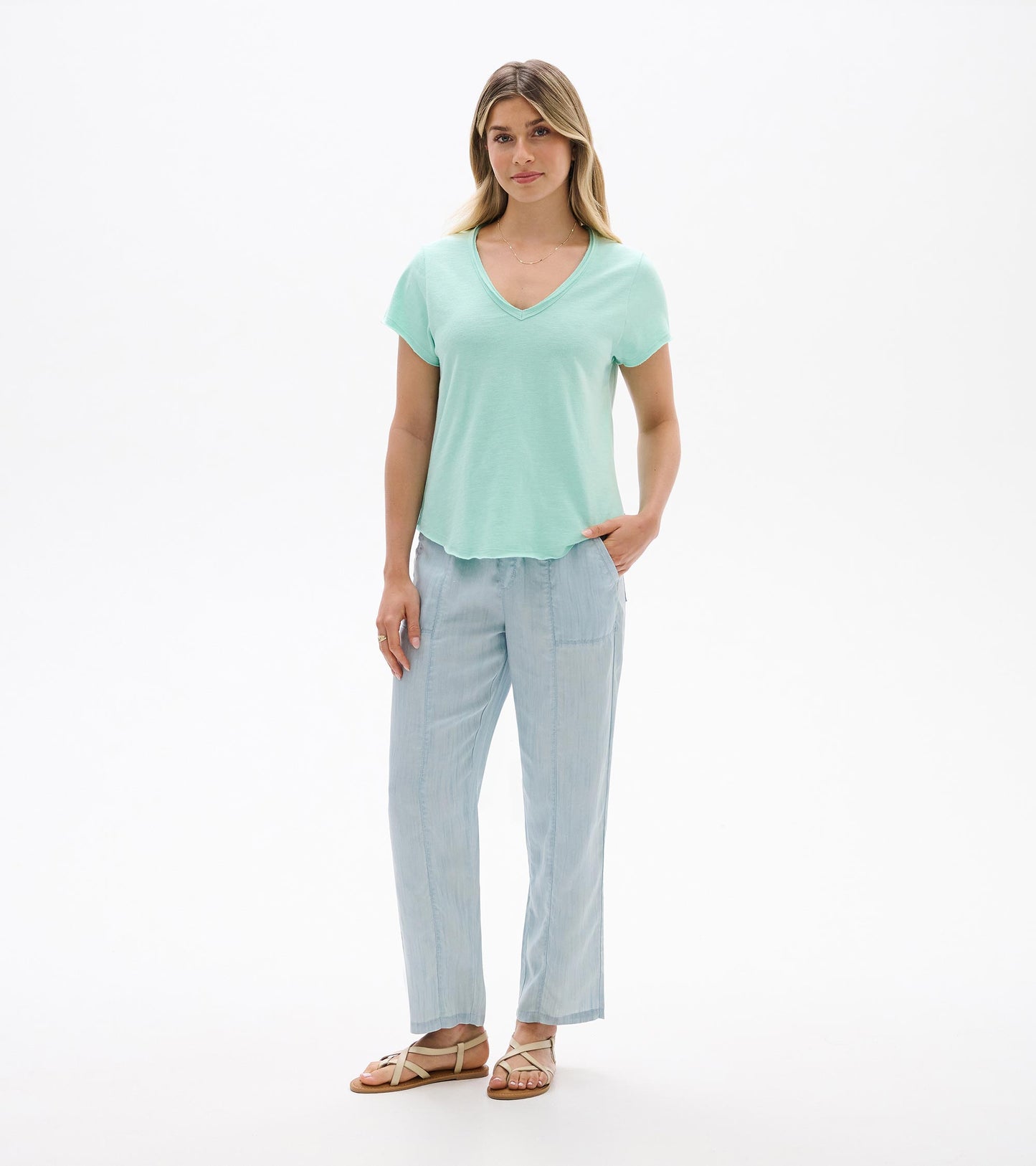 Woman wearing a sea glass mint V-neck short-sleeve tee with a relaxed fit and curved hem, front view.