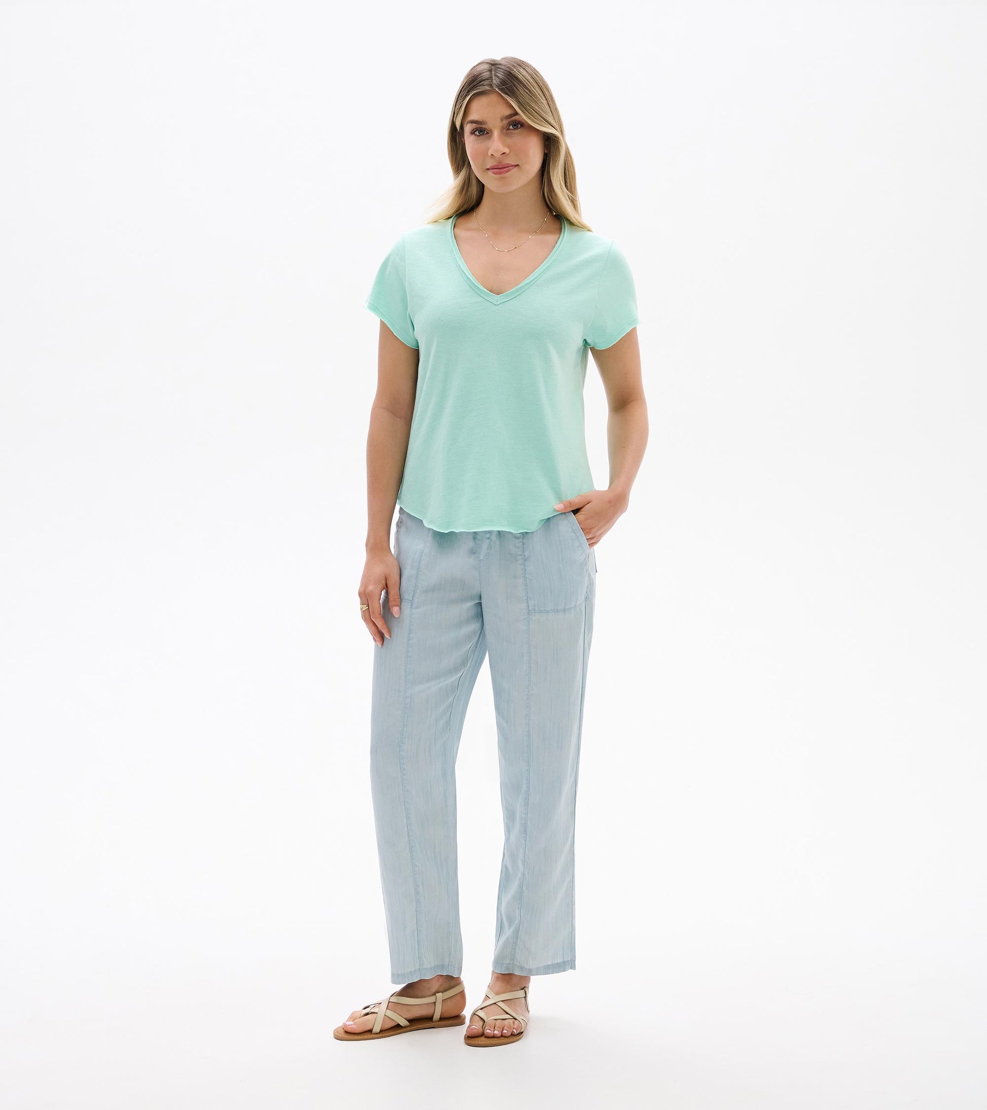 Woman wearing a sea glass mint V-neck short-sleeve tee with a relaxed fit and curved hem, front view.