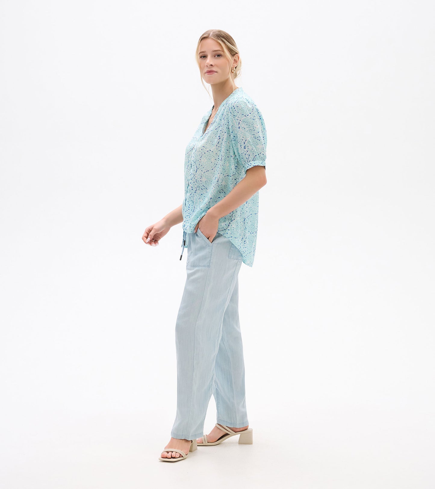 Light blue patterned short-sleeve blouse with V-neck, shown on model in side view