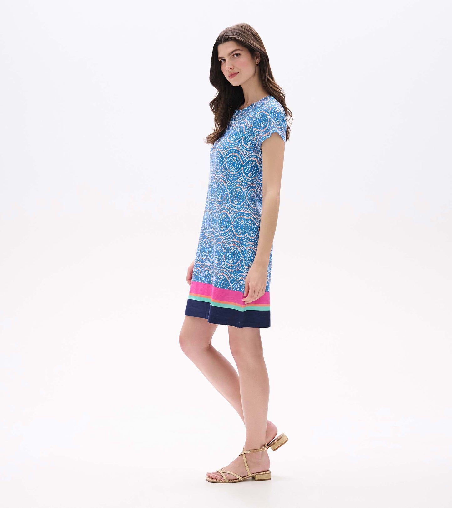 Side view of blue and white ikat tee dress with short sleeves and pink, aqua, and navy border hem