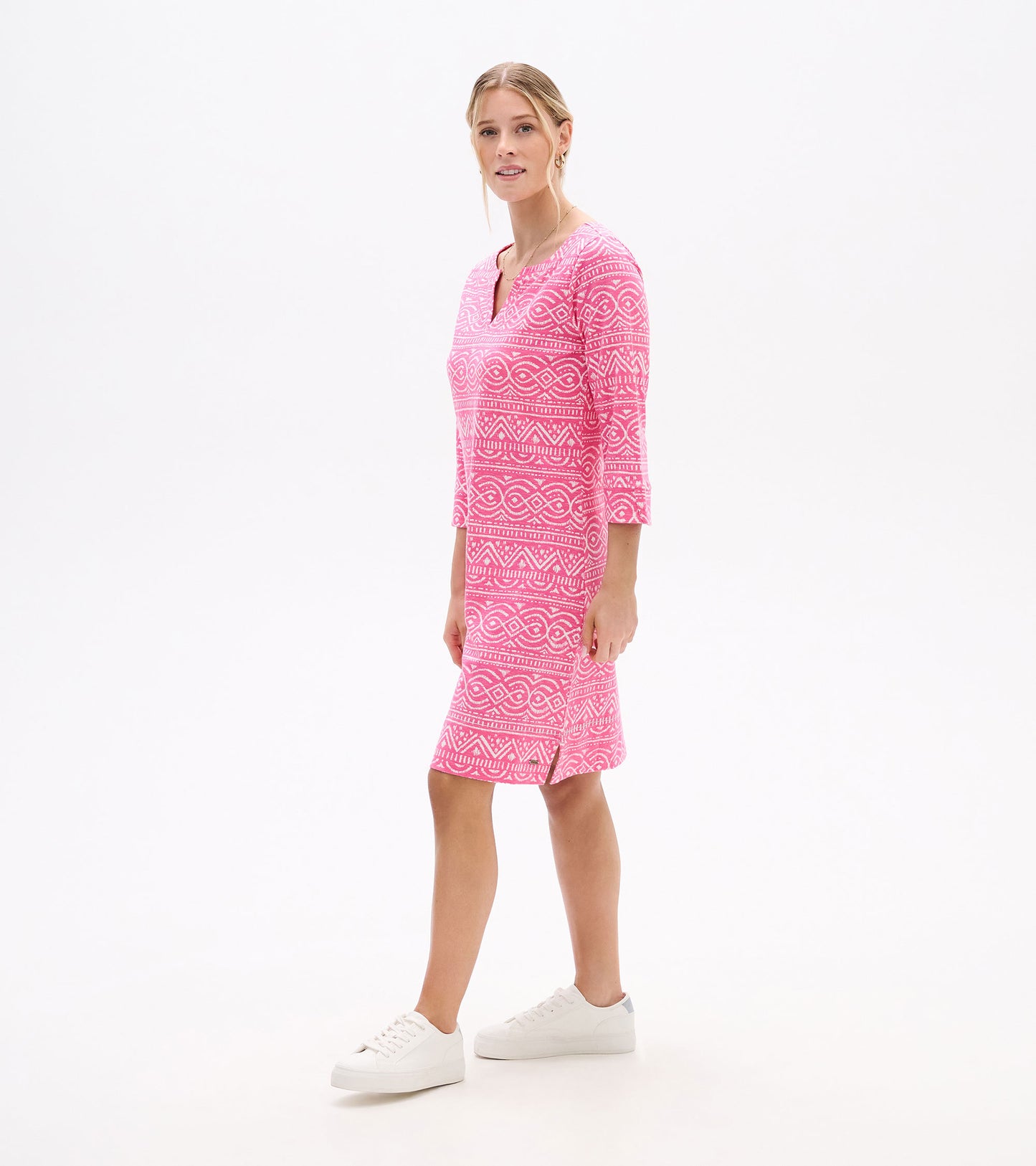 Side view of pink notch neck dress with white geometric line pattern, three-quarter sleeves and side slit
