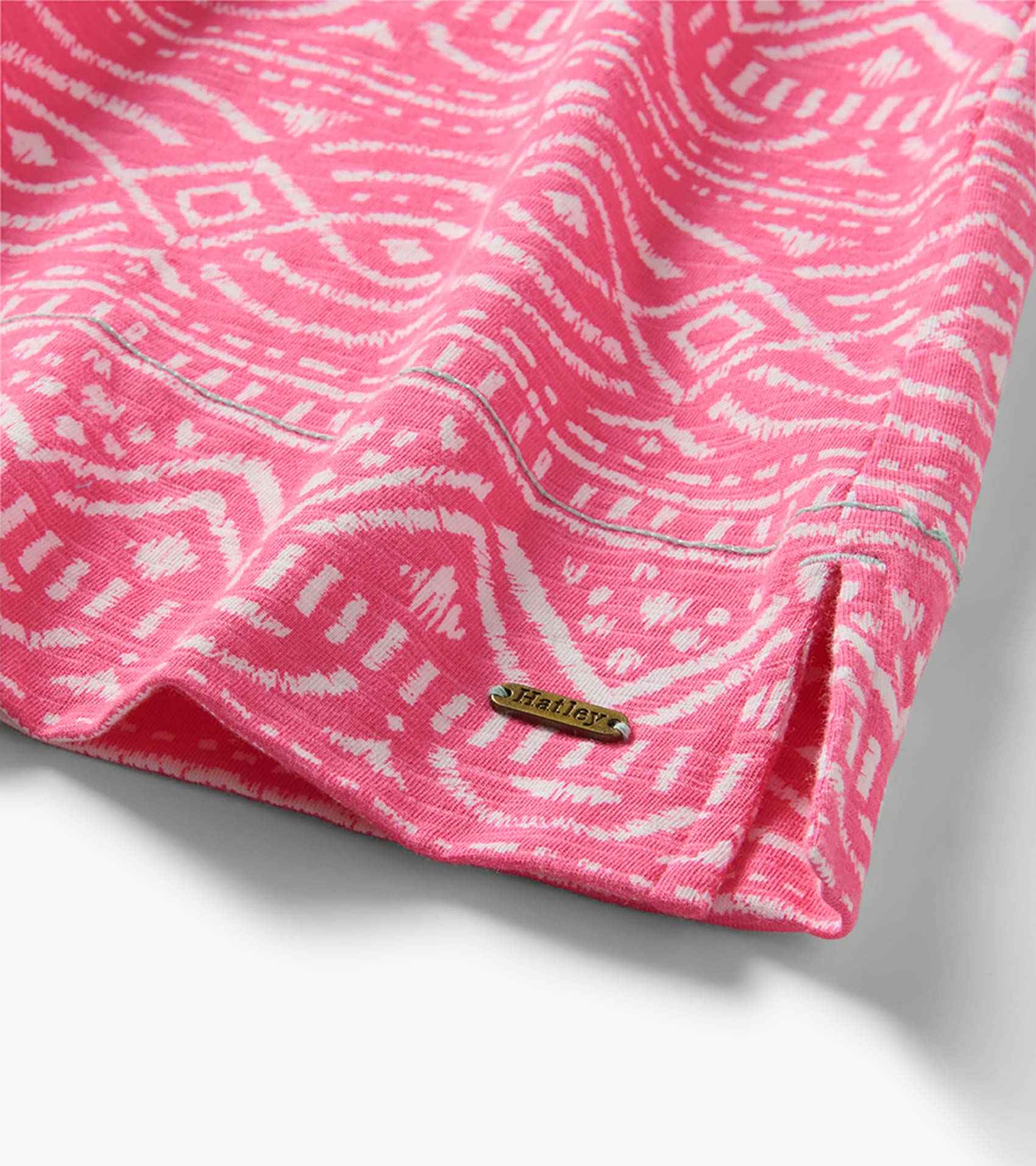 Close-up of pink and white sketched line pattern dress hem with visible Hatley metal logo tag