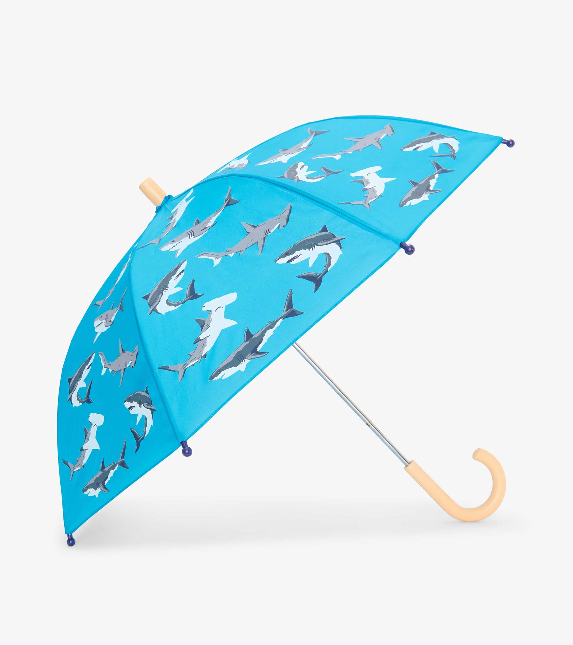 Blue kids umbrella with shark print, tan curved handle, and silver shaft on white background