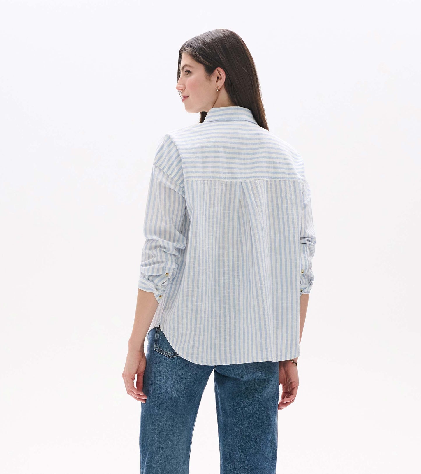 Back view of relaxed button-down shirt in pale blue and white stripes with curved hem and back pleat