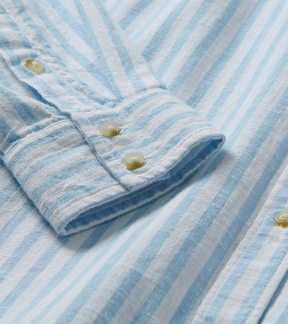 Close-up of cuff and placket on pale blue and white striped button-down shirt with light buttons