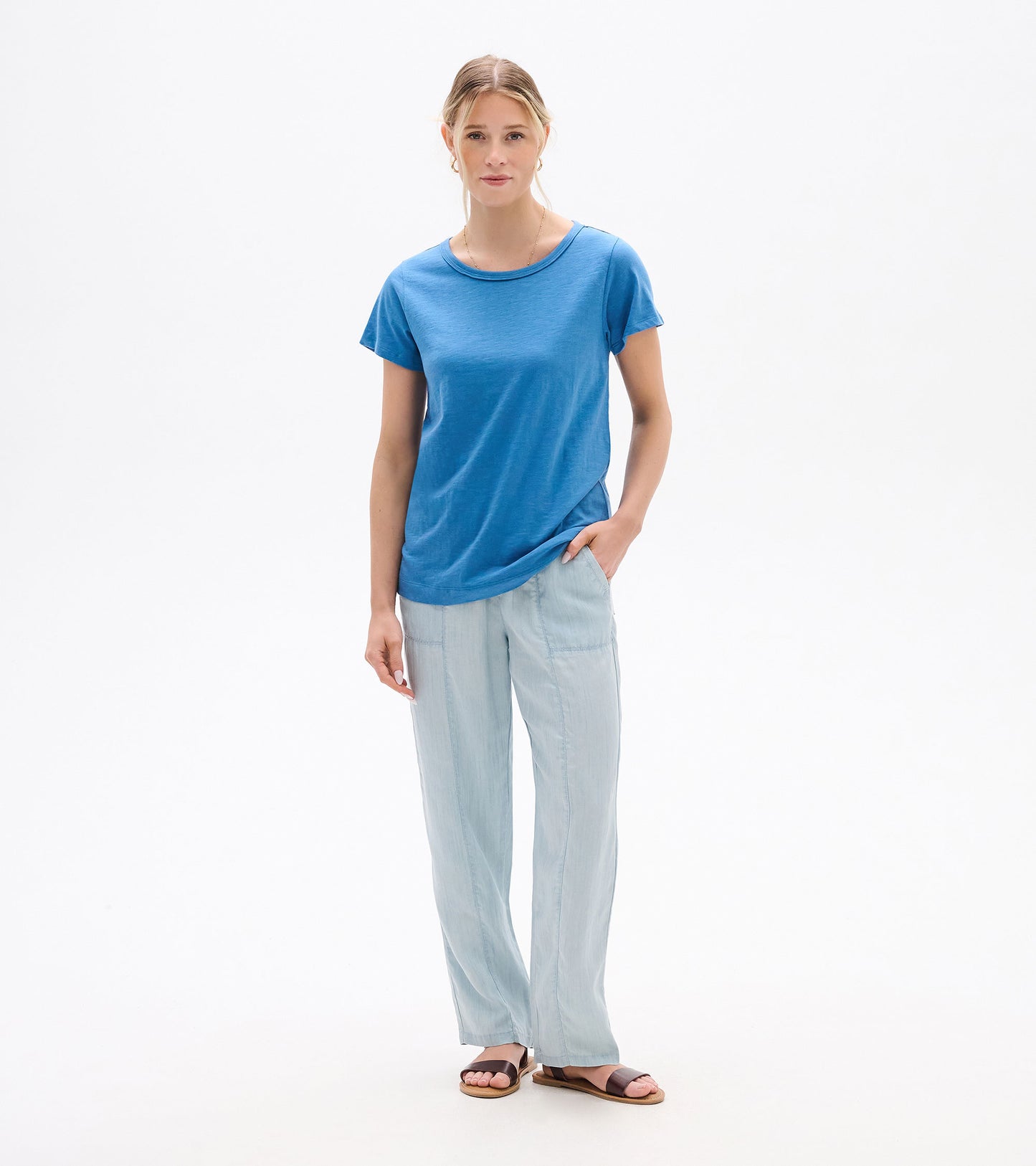 Woman wearing a star sapphire blue crew neck short-sleeve tee with a relaxed fit and rounded hem, front view.