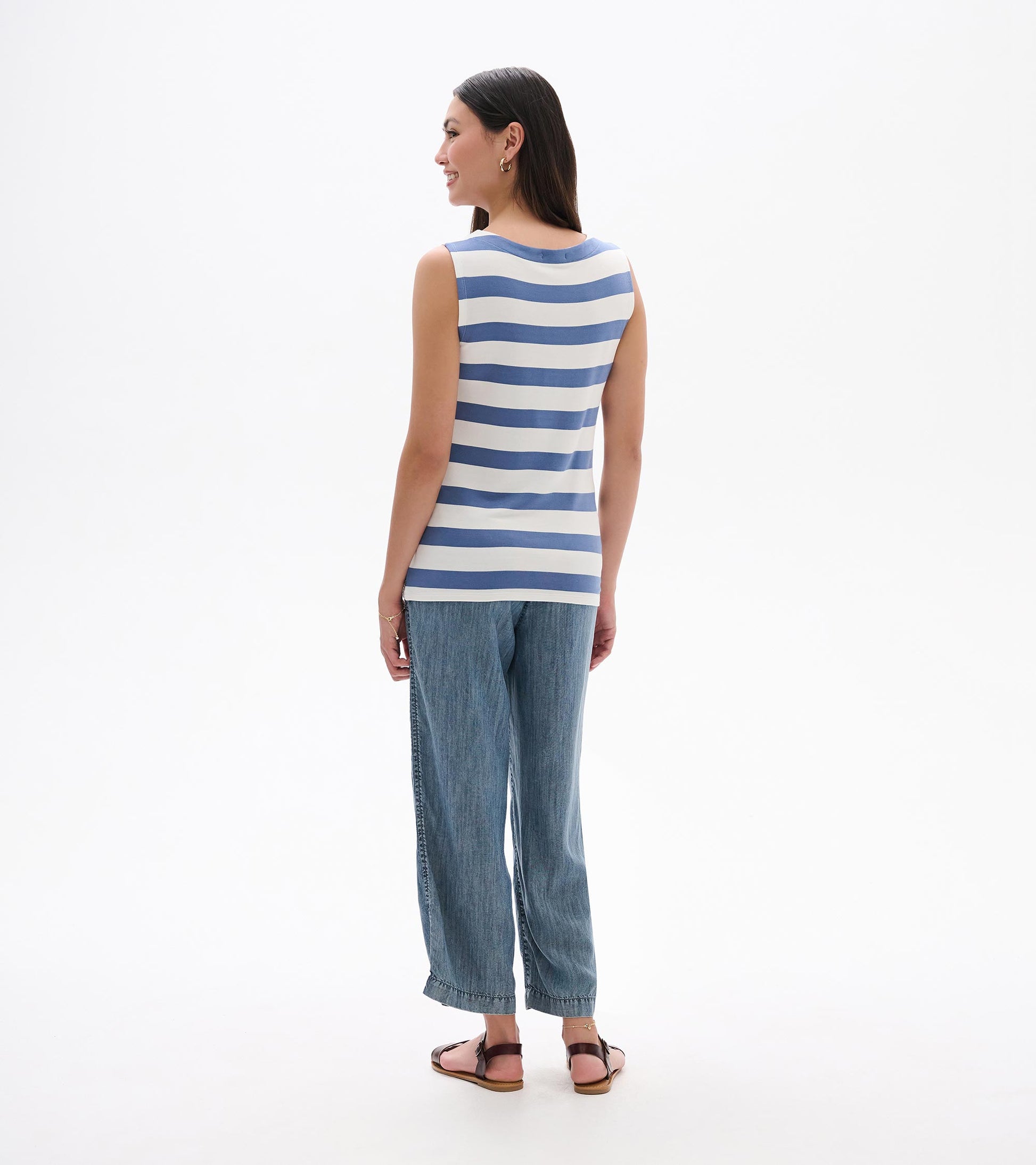 Back view of a sleeveless blue-and-white striped tank top worn with wide-leg jeans and sandals