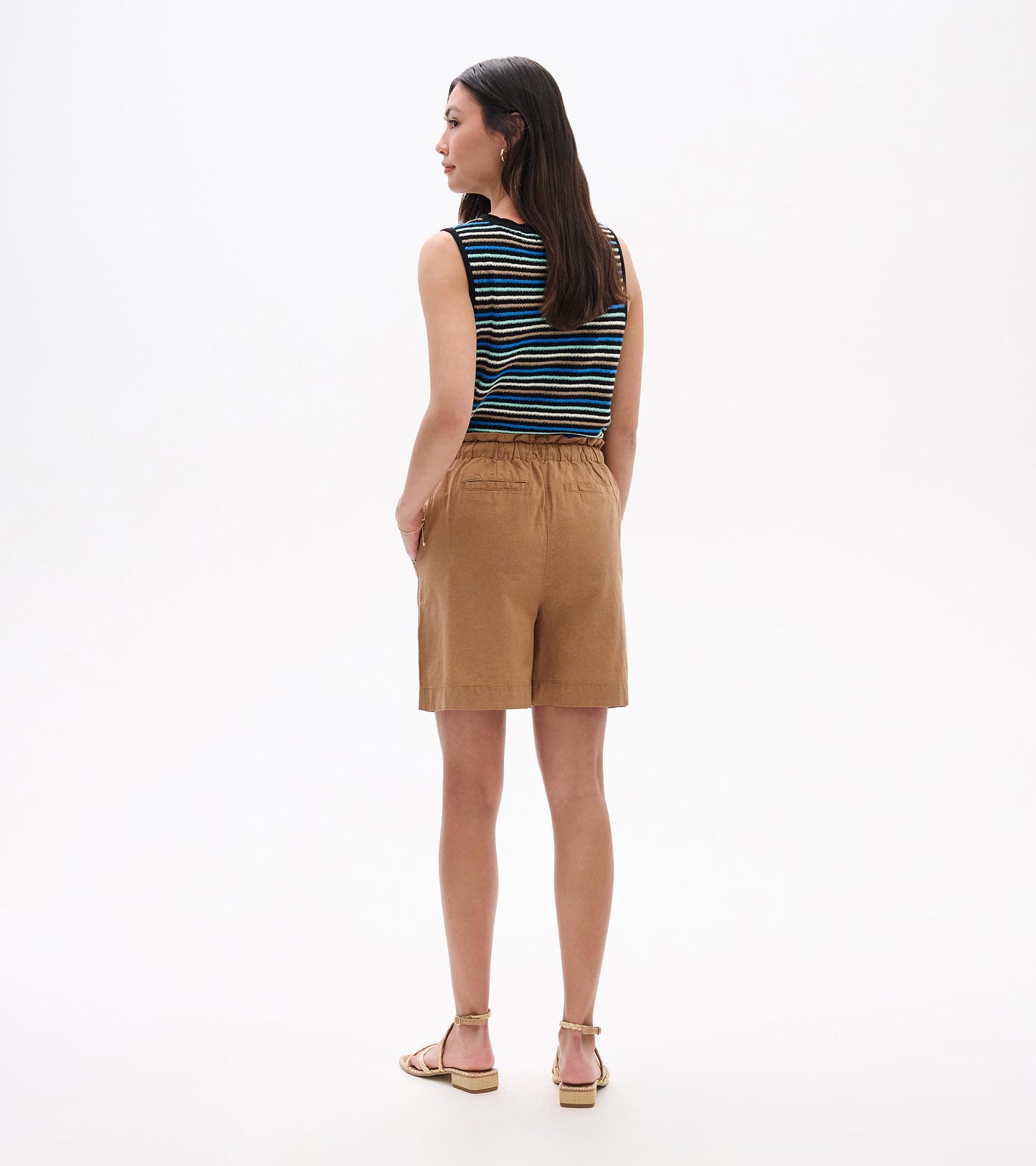 Back view of tan knee-length shorts with elastic waistband and pockets on a model