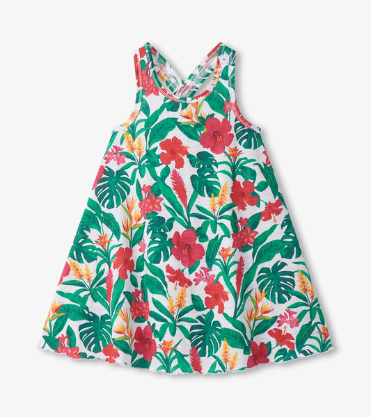 Girls white trapeze dress with green tropical leaves and red floral print, sleeveless with scoop neckline