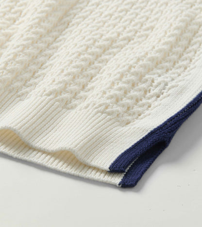 Close-up of a cream knit tank top with textured stitching and navy trim at the hem and side seam