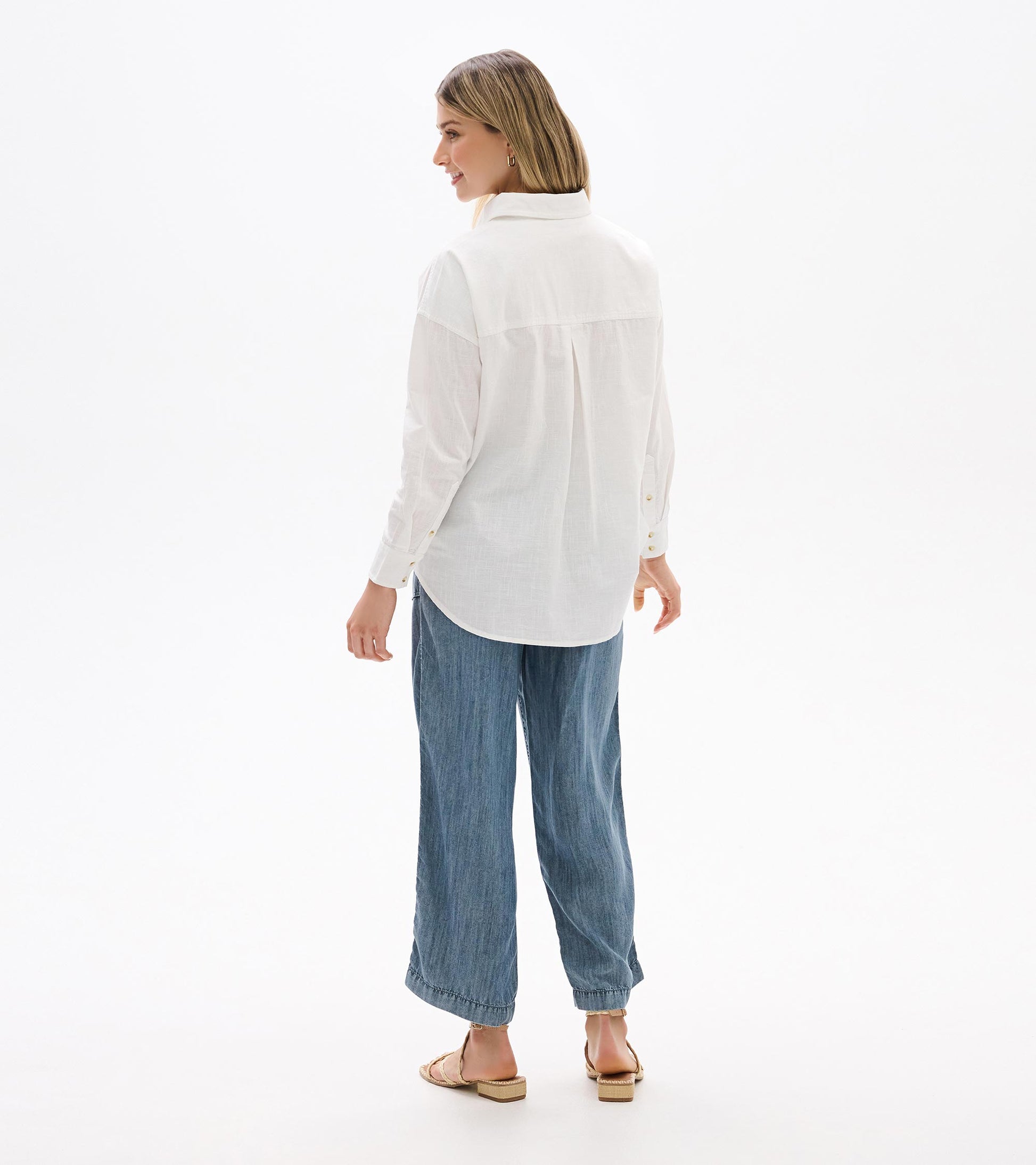 White relaxed button-down shirt on model, back view with center pleat and curved hem
