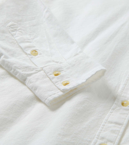 Close-up of white button-down shirt cuff with pale buttons and subtle textured weave