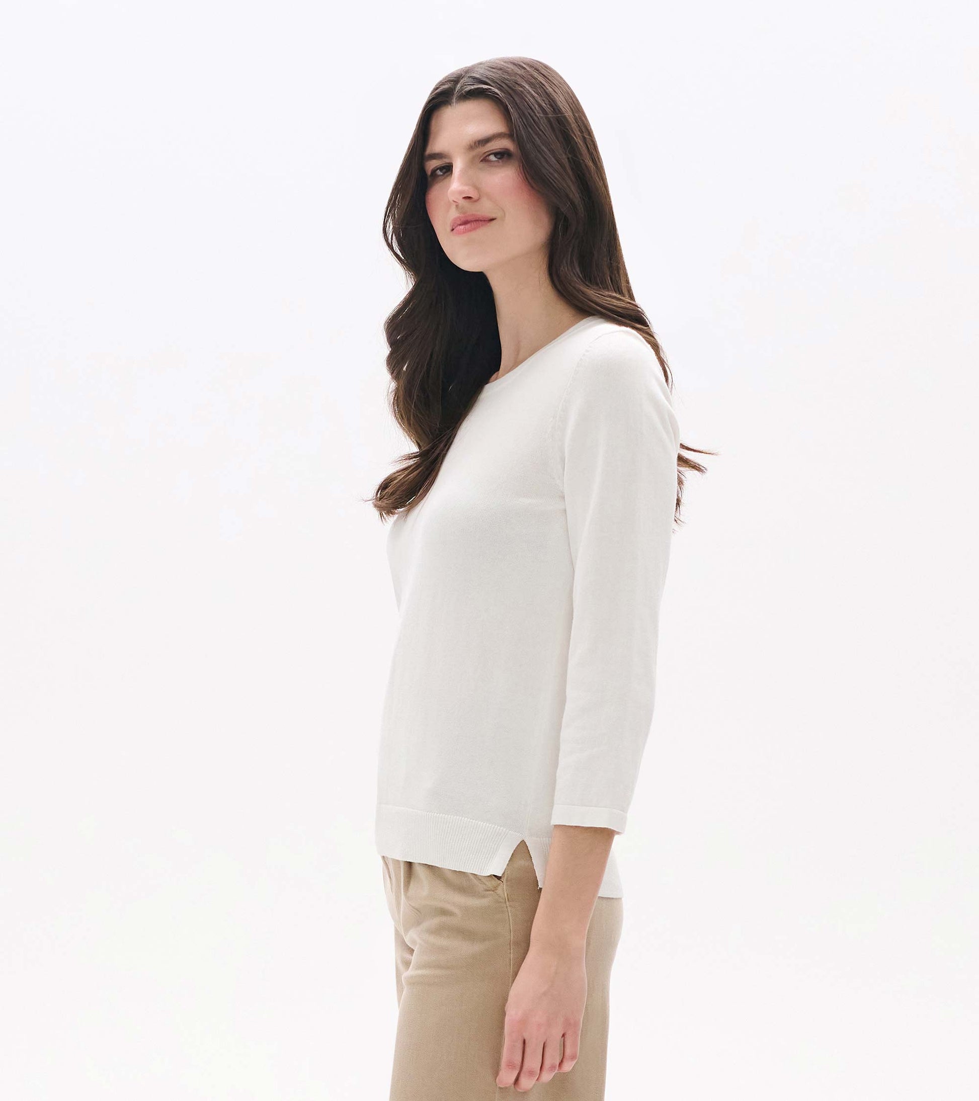 White knit top with 3/4 sleeves, crew neckline, and side slit hem, shown on a model in side view.