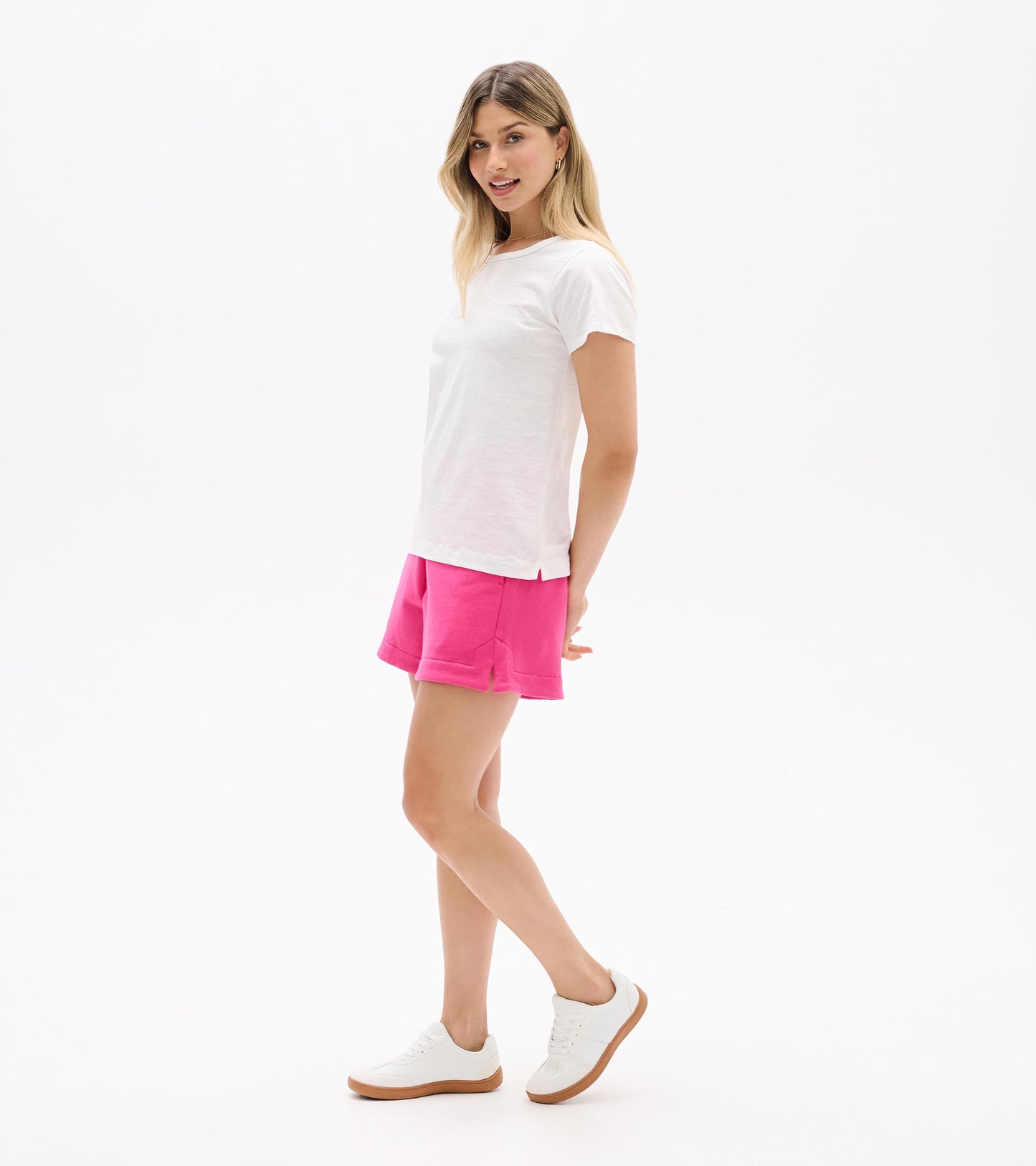 White crew neck short-sleeve tee worn with pink shorts, shown on a model in side view