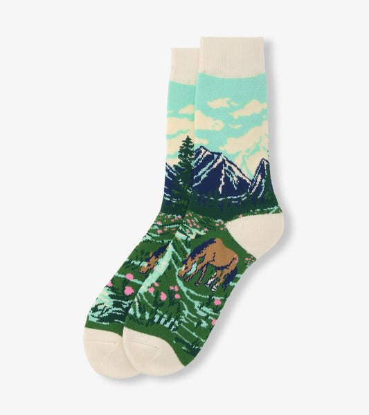 Pair of cream crew socks with mountain, trees, and grazing horse landscape pattern