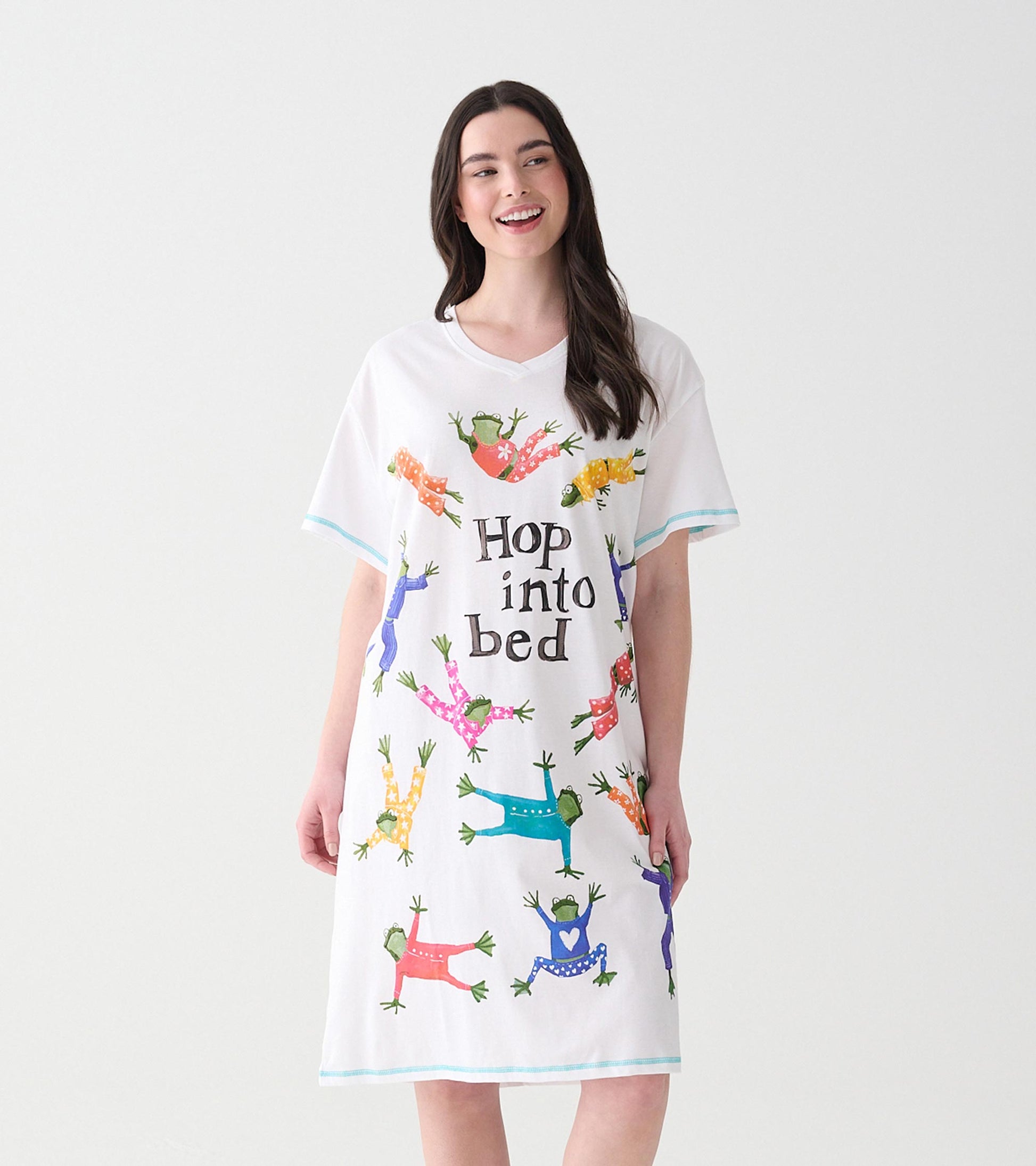 Woman wearing white V-neck sleepshirt with colorful frogs in pajamas and 'Hop into bed' text