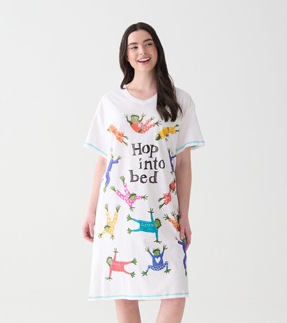 Woman wearing white V-neck sleepshirt with colorful frogs in pajamas and 'Hop into bed' text