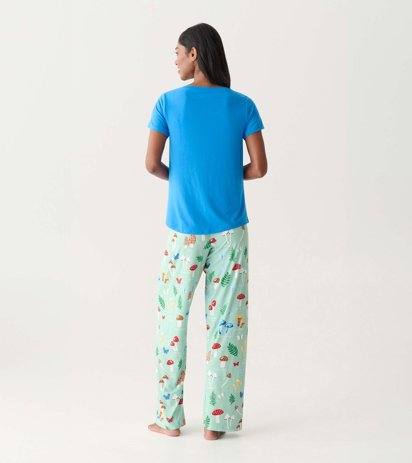 Back view of a blue V-neck T-shirt with short sleeves, paired with mint green mushroom-print pajama pants.