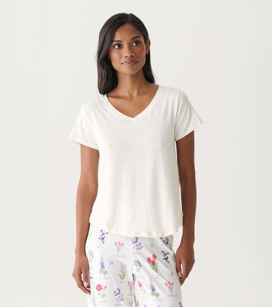 Woman wearing a cream V-neck short-sleeve T-shirt and floral pajama pants, front view