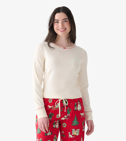 Model wearing a cream long sleeve top with red trim at the neckline and cuffs