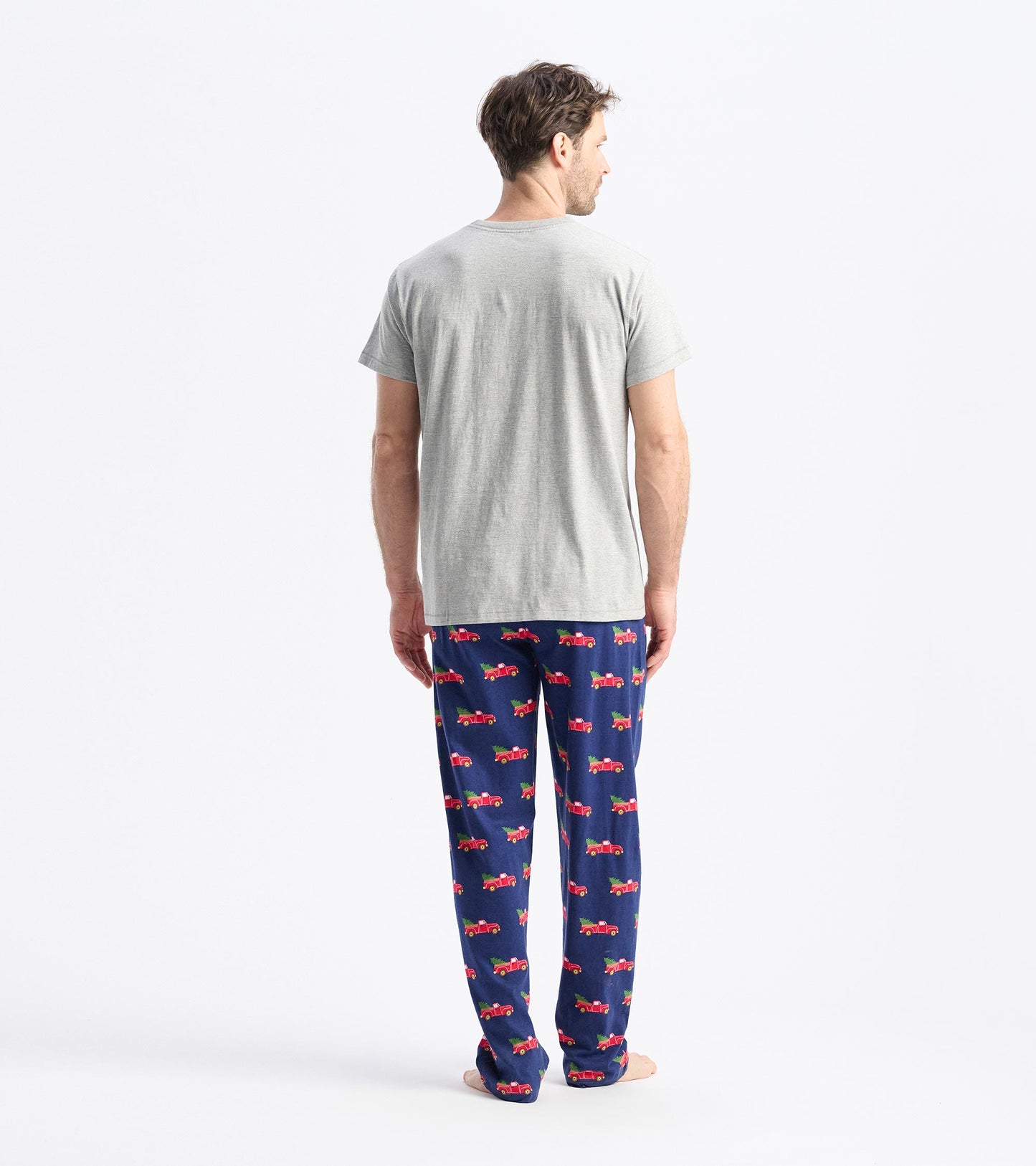 Gray short-sleeve t-shirt worn with patterned pajama pants featuring red trucks on a navy background.