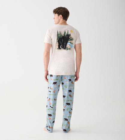 Full back view of oatmeal T-shirt with black bear wilderness graphic, worn with blue wildlife print pants