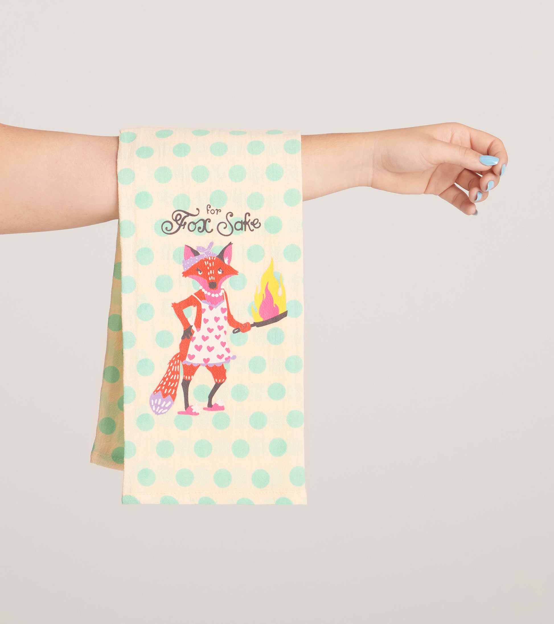 Tea towel featuring a whimsical fox in a pink dress with hearts, holding a flaming pan, set against a mint polka dot backgro…