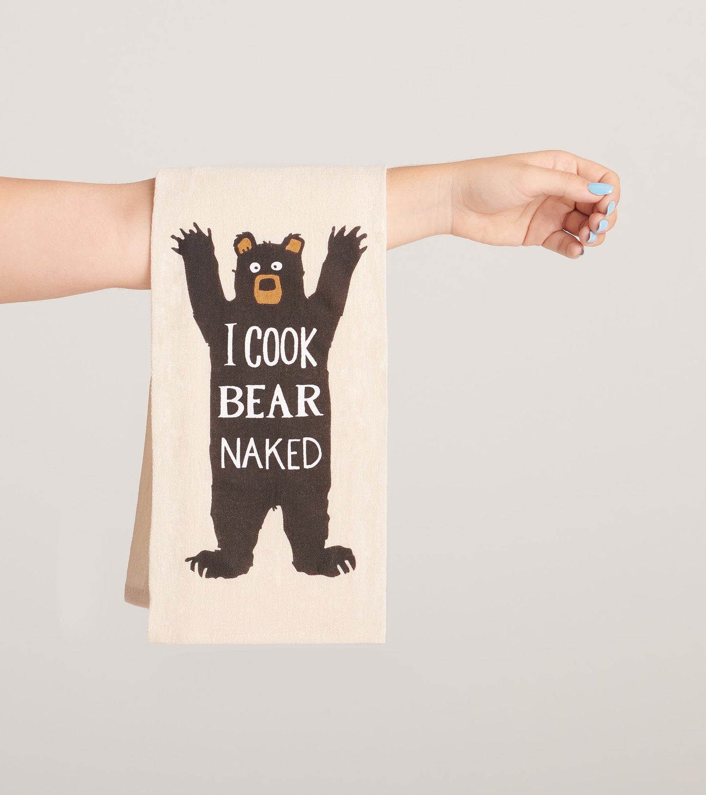 Beige tea towel featuring a black bear graphic with the text "I Cook Bear Naked," held by a hand.